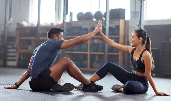 Motivation, celebrate and support with fitness coach doing high five with woman in the gym. Active and fit woman training or practicing strength and stamina workout with her friend in a health center.