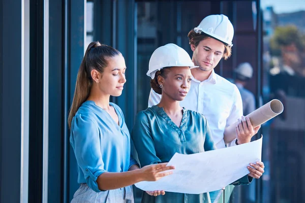 Engineer, architect or designer team looking at blueprint, design layout paper for construction building outside. Diverse city planner or business people with architecture development or floor plan.