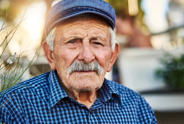 He is been living in this town forever. Portrait of a confident senior man standing outside while looking at the camera