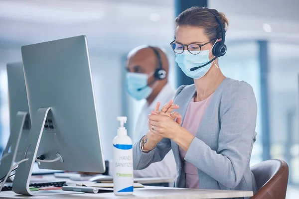 Covid, hand sanitizer and call center agent with mask cleaning hands, protecting or staying safe in customer support office. Receptionist, advisor or operator with computer preventing spread of virus.