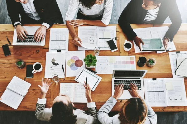 Overhead of colleagues having a marketing meeting in modern office. Above a busy workplace, coworkers brainstorm and develop strategies for a startup business, unity, planning and innovation at work.