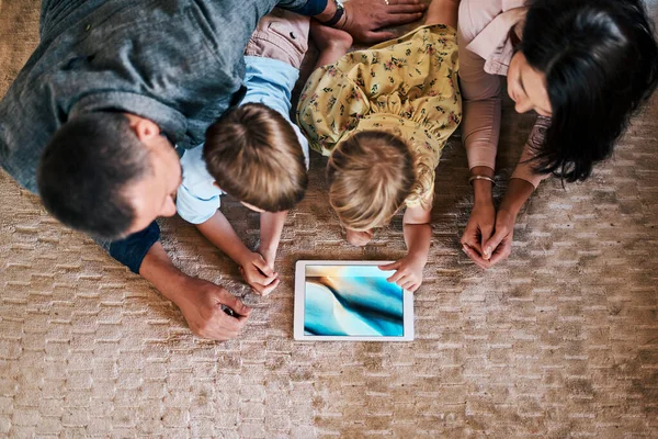 The connection we have with family is the most important. a young family of four using a digital tablet together at home