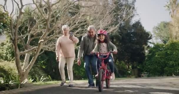Возбужденная Счастливая Маленькая Девочка Учится Кататься Велосипеде Своими Возбужденными Бабушкой — стоковое видео