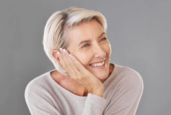 Thinking, idea and memory with a senior woman resting her head or chin on her hand in studio on a grey background. Skincare, health and beauty with a female looking to wellness and lifestyle.