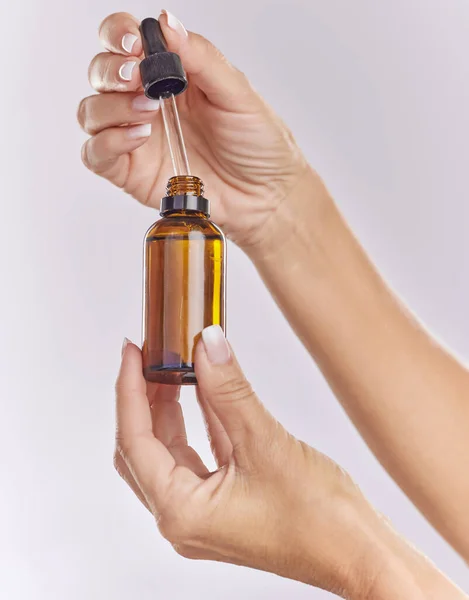 Skincare serum, essential oil and cosmetic product in woman hand for perfect, smooth skin or reduce wrinkles isolated on studio background. Closeup hands using body care or anti aging liquid drop.