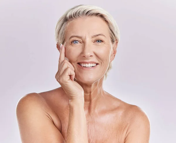 Senior woman applying beauty sunscreen, face cream or moisturizing lotion on skin isolated on studio background. Portrait skincare, health and wellness lady with wrinkles and anti aging moisturizer.