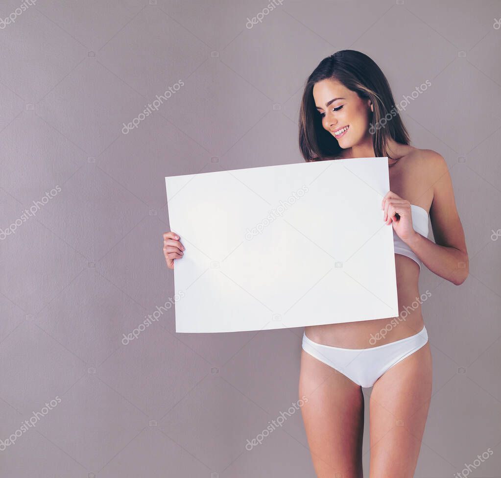 Well, would you look at that...Studio shot of an attractive young woman holding a blank placard against a pink background