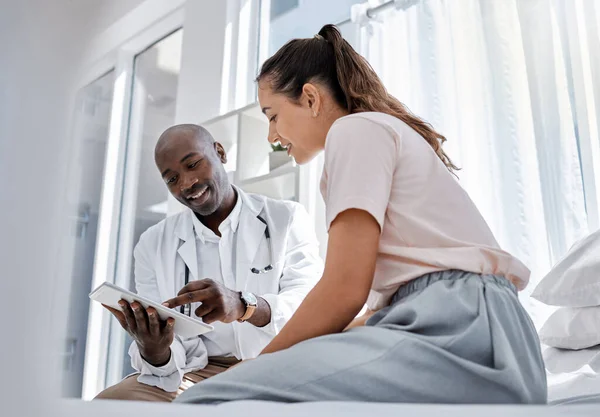 Doctor appointment or healthcare professional consulting a patient and showing her online medical results on a tablet. Medical worker or GP talking to a woman in a hospital or clinic.