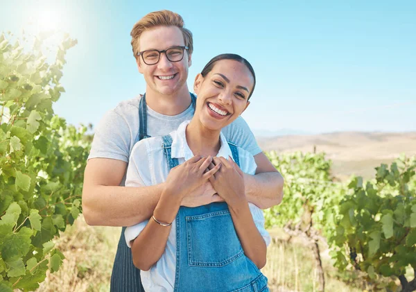 In love, countryside and farmer couple enjoying grape vine plant growth development in summer with flare or sunlight and blue sky. Happy, young rustic people hugging on a sustainable farm or vineyard.