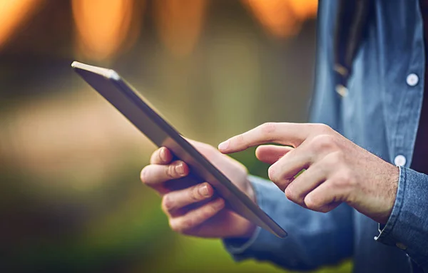 Connected to the outside world with just a touch. an unrecognizable man using a tablet outdoors