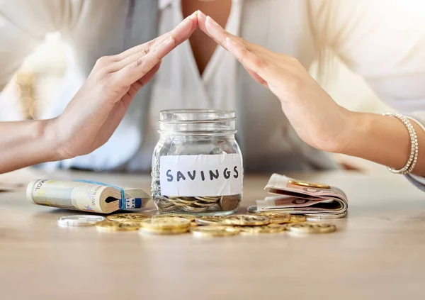 Savings, investment and insurance cover business woman with coins, money and cash in a jar for future plan or personal growth development or housing. Closeup hands covering bank or mortgage expenses.