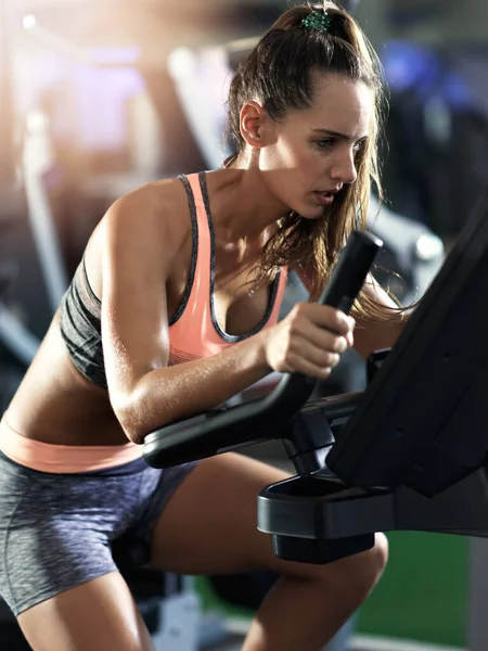 Your hard work determines your end result. a determined looking young woman working out on an elliptical machine in the gym