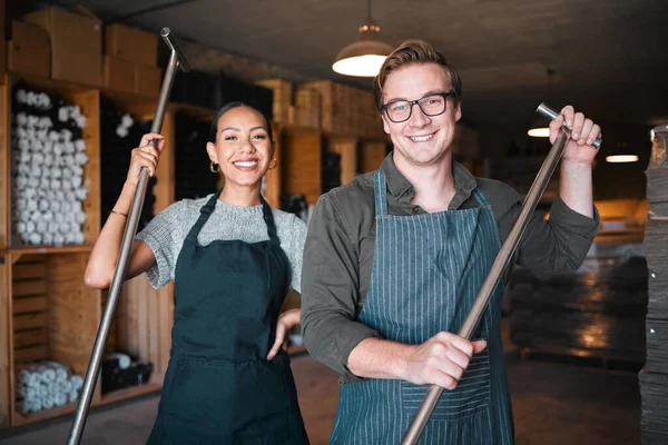 Wine making workers with press tool or equipment inside a cellar, winery or distillery warehouse with bulk quality alcohol. Woman, man or sommelier people with smile portrait for industry background.