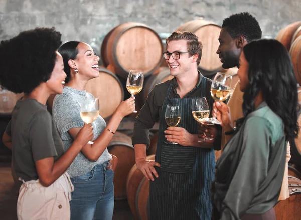 Group of friends wine tasting at a distillery or cellar drinking glasses and enjoying the tour together. Happy, carefree and diverse people bonding and having fun at a winery estate.