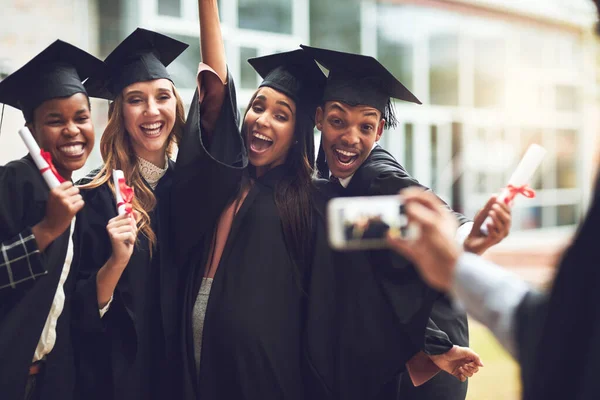 The perfect pose for the last picture. fellow students taking a picture together on graduation day