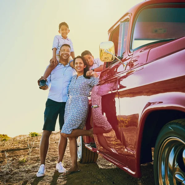 Ready to get on the road. a cheerful family posing for a portrait together outside next to a red pickup truck