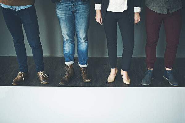 Stand tall and true to yourself. Studio shot of a group of unrecognisable people standing in a row against a grey background