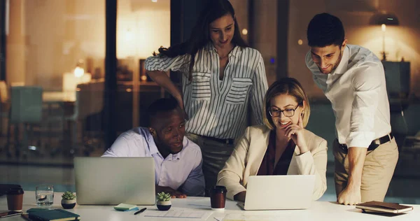 Theyre making progress. a group of businesspeople gathered around a laptop in their office