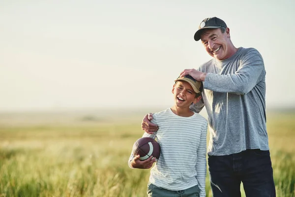 Dads the best coach. father and son playing with a football on a field