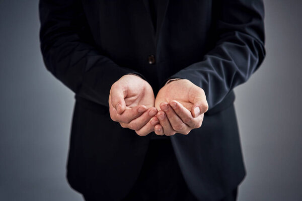 Help, please. Cropped studio shot of a businessman with his hands open against a gray background