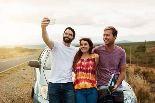 Lets take our first photo together for the trip. a group young friends getting in close or a self portrait photo while standing next to a road