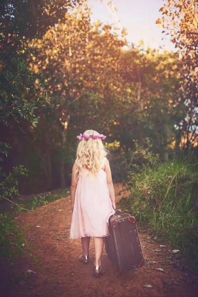 Ive got everything I need. a unrecognizable little girl walking with a suitcase on a dirt road outside in nature