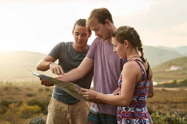 Searching for something undiscovered. three young hikers consulting a map while exploring a new trail