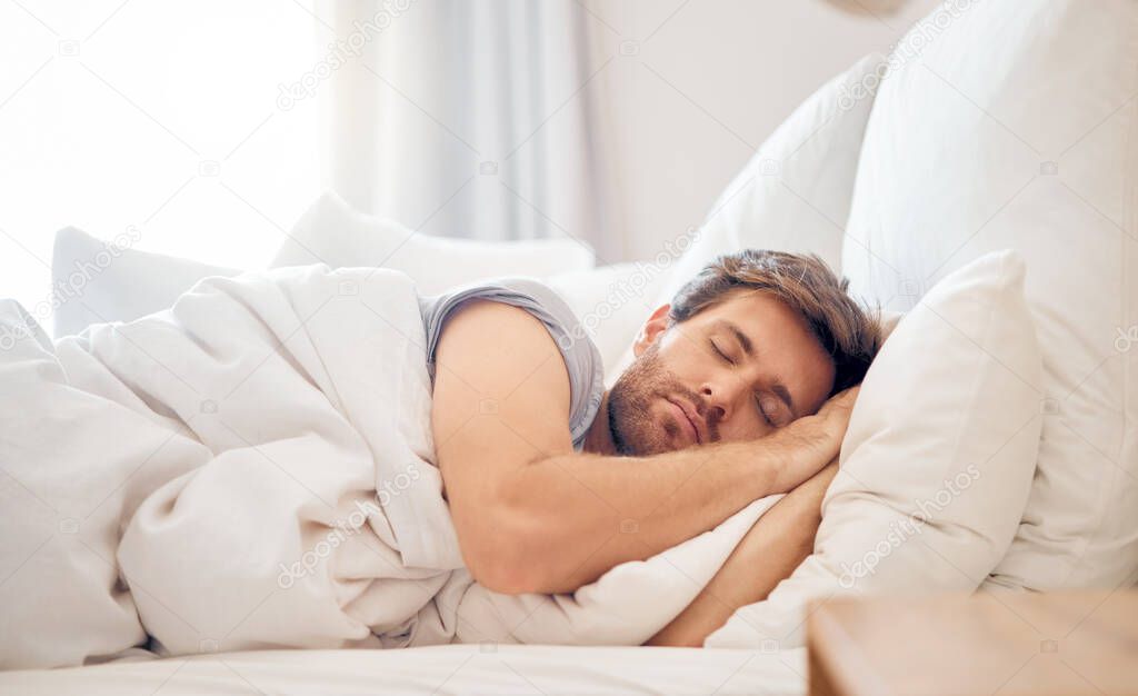 Home, bedroom and sleeping man in the morning lying his head on the pillow in apartment space. Tired, fatigue and relax male taking time off on the weekend in bed of airbnb or hotel accommodation.