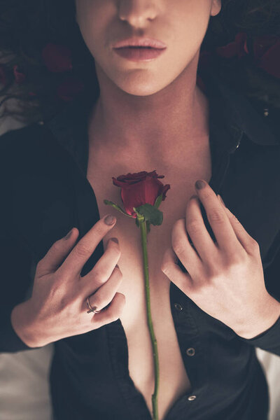 Let your sensuality bloom. High angle shot of an unidentifiable young woman opening her shirt in bed to reveal a rose on her chest