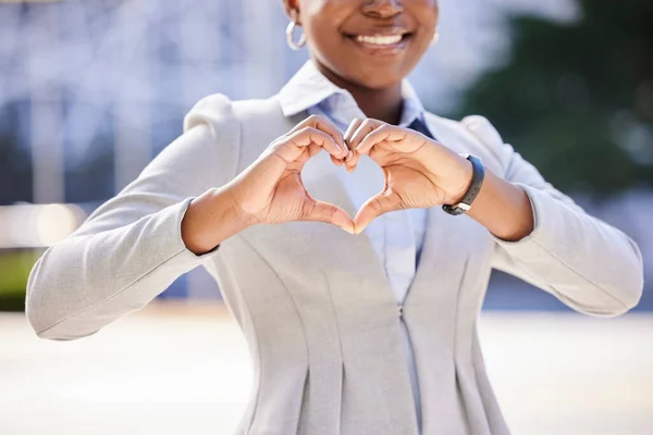 Love and a smile, a business woman makes a heart sign with her hands. Black, corporate office worker and a gesture of respect and friendship with her fingers, happy with work and success in the city.