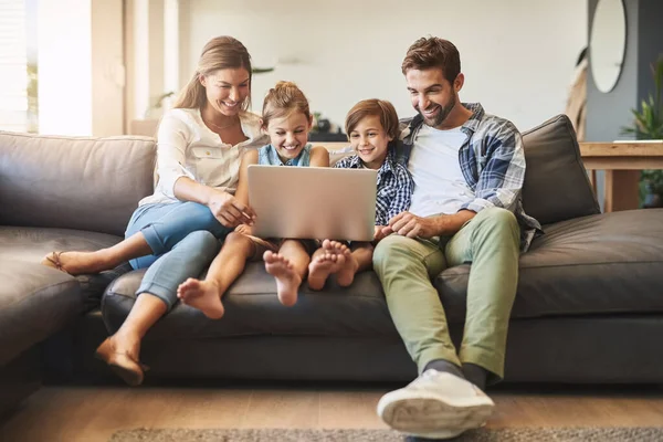 Theres lots to learn online. a mother and father using a laptop with their son and daughter on the sofa at home