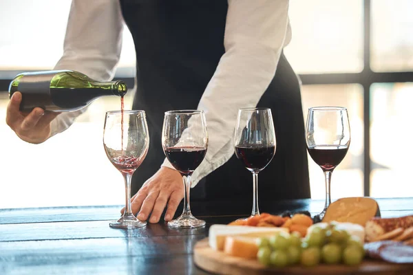 Luxury, fine dining and hospitality with a waiter pouring red wine at a restaurant. Preparing for a wine tasting with a professional sommelier, good service with quality drink by a male winemaker.