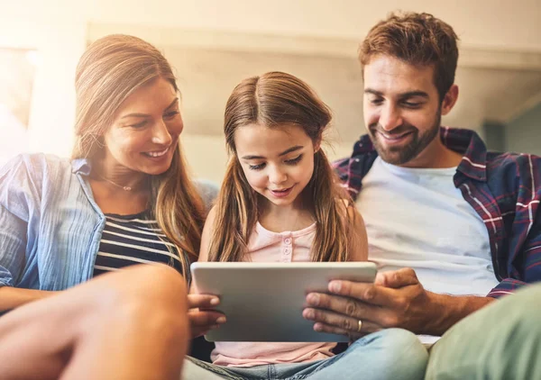 Bonding time meets screen time. a mother and father using a digital tablet with their daughter on the sofa at home