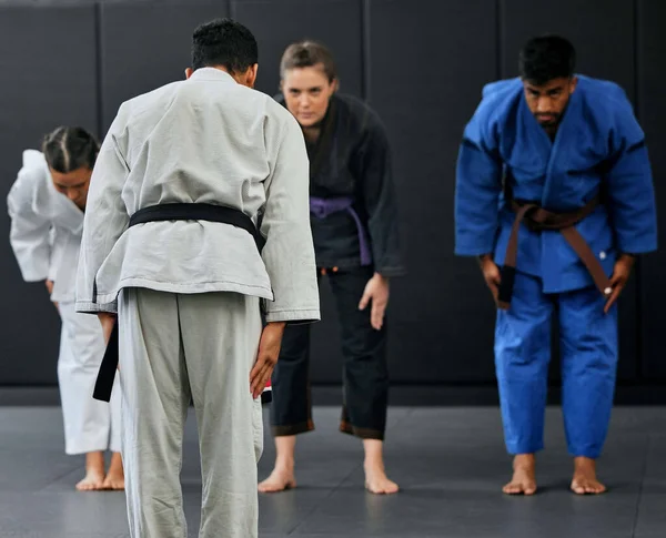 Fitness, strength and respect between karate trainer leading a class, bow and greeting martial arts student at a dojo or studio. Diverse group training and learning self defense and endurance skills.