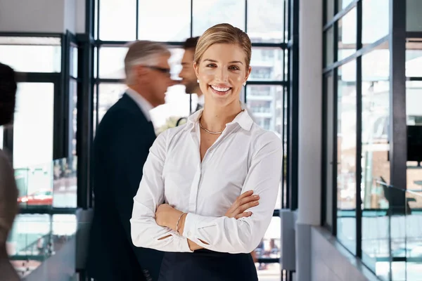 Hard work has made her one of the standouts in business. Portrait of a young businesswoman standing in a busy office