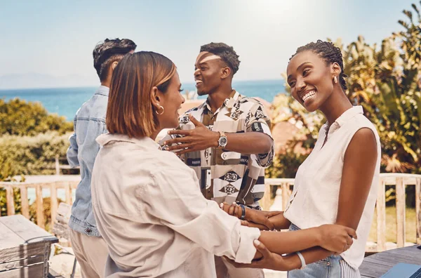 Friends, hugging and looking happy while meeting outside a restaurant. Diverse couples talking and greeting while on a double date. Friendly women and men embracing while having fun at a gathering.