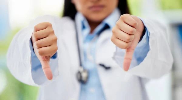 Doctor with thumbs down hand sign in healthcare hospital or lab for fail, poor health insurance or death statistics. Zoom of unhappy, bad loss or loser hands emoji icon of a healthcare professional.
