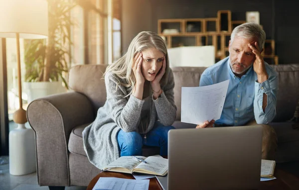 How did we manage to blow our budget so quickly. a couple looking anxious while doing their budget at home