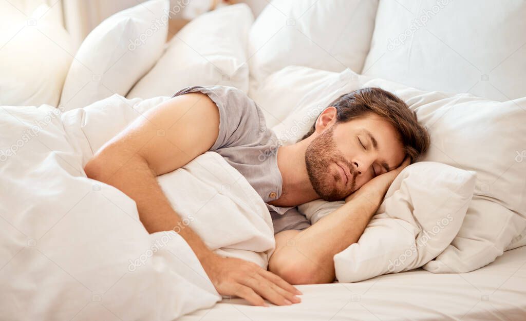 Relax, sleep and peace of a tired man sleeping in a bedroom bed at home. Dreaming, relaxing and resting calm attractive person with closed eyes on a pillow at his house in the morning taking a nap.