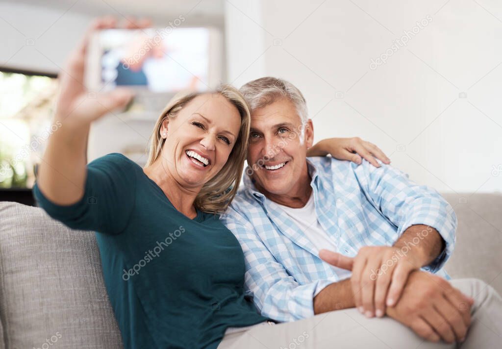 Smile. an affectionate mature couple taking selfies together while sitting on the sofa at home