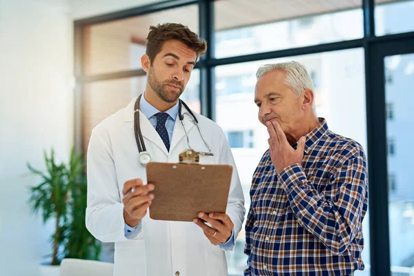 Im a little worried about your test results. a doctor and his mature patient considering test results on a clipboard in the hospital