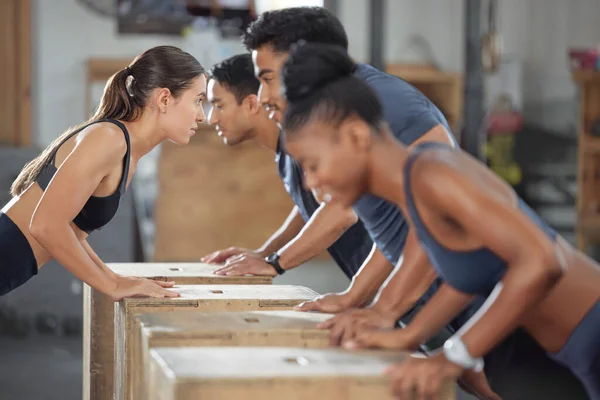 Fitness, exercise and accountability group training and exercising together with wooden boxes at the gym. Diverse people and fit athletic friends looking serious and cross during a workout.