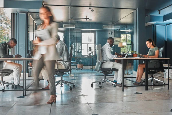 Work process of busy corporate team of business people working at startup marketing company, planning email on laptop and sitting at desk in office. Blur of employees, workers and businesspeople.