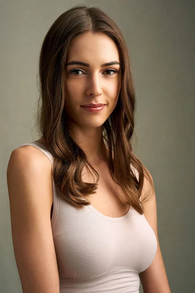 Beauty, its simple. Studio portrait of an attractive young woman standing against a brown background