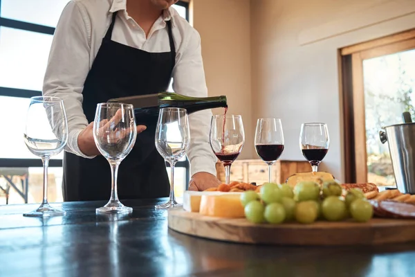 Hospitality, industry, and luxury wine service with waiter pouring in glasses, prepare for wine tasting at restaurant. Professional sommelier setting up for fine dining experience with alcohol.