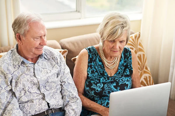 Close to home and to the outside world. a senior couple using a laptop together on the sofa at home