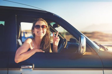 I found myself on the open road. Cropped portrait of an attractive young woman showing a piece sign while on a roadtrip