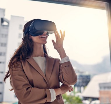 Logged into the virtual domain. a young businesswoman wearing a VR headset in an office