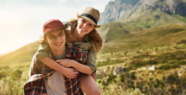 Ill carry her up any mountain to make her smile. Portrait of a happy young couple enjoying a piggyback ride in nature