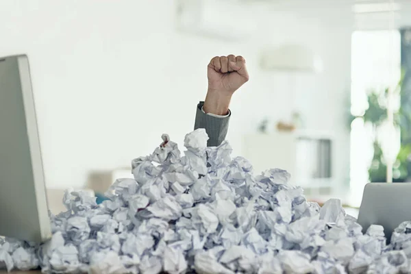 Fighting his way through the paperwork. an unidentifiable businessman drowning under a pile of paperwork in the office